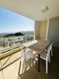 una mesa de madera y sillas en un balcón con vistas en Bel appartement neuf vue mer, en LʼÎle-Rousse