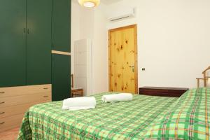 a bedroom with a green bed with two pillows on it at Acquamarina32 in San Vito lo Capo