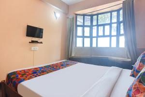 1 dormitorio con cama, ventana y TV en FabEscape Aqualura Verem With Swimming Pool en Nerul