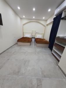 two beds in a room with a tile floor at Saraya Abbas ELaser Street-families only in Alexandria