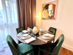 a dining room table with green chairs and a painting at A Gem Next to Selfridges in London