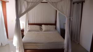 a bedroom with a canopy bed with white curtains at Casa Terravista Trancoso in Trancoso +26 photos