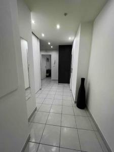 a hallway with a black vase sitting on a tile floor at Très bel appartement entre Paris et Disneyland in Lognes