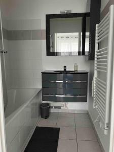 a bathroom with a sink and a tub and a mirror at Très bel appartement entre Paris et Disneyland in Lognes