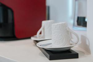 two white cups and saucers sitting on a counter at Casa Luís de Camões - Boutique & Literary House in Santar