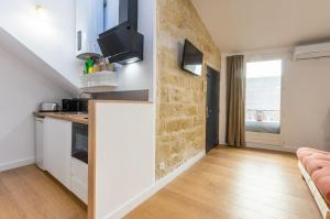 uma cozinha com armários brancos e uma parede com uma televisão em Petit coeur de ville - Premiere conciergerie em Montpellier