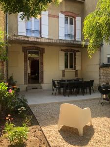 una sedia bianca seduta di fronte a una casa di Maison et jardin à Epernay centre ville a Épernay