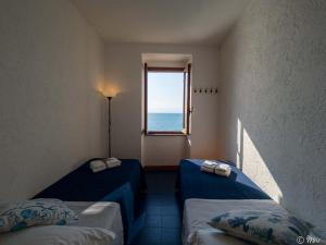 two beds in a room with a window at La Lampara Sea View Terrace Apartment in Manarola