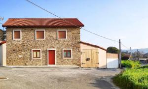une maison en briques avec une porte rouge dans une rue dans l'établissement AG Casa Rural Carballo jardín y playa a 14km, à Artes