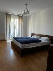 Schlafzimmer mit einem Bett mit blauer Bettwäsche und einem Fenster in der Unterkunft LeoApart Czysta in Breslau