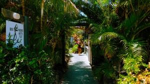 a path through a garden with palm trees and a sign at Backpackers at 1770 in Agnes Water