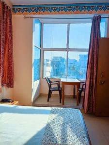 een slaapkamer met een raam en een tafel en stoelen bij Hotel Braj Haveli in Jaipur