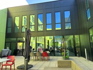 un edificio con sillas rojas y mesas en un patio en Campanile Belfort Montbéliard - Gare La Jonxion., en Meroux