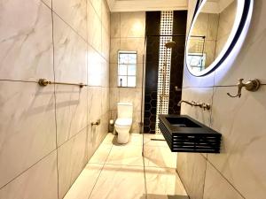 a bathroom with a toilet and a sink and a mirror at The Lux Guesthouse in Kroonstad