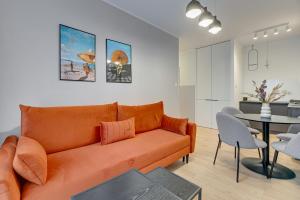 a living room with an orange couch and a table at Downtown Apartments City Center Angielska Grobla in Gdańsk