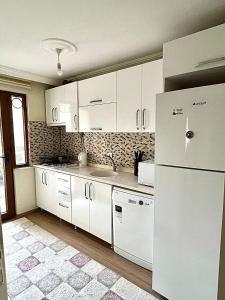 uma cozinha com armários brancos e um frigorífico branco em Halic Apart Hotel em Yalova