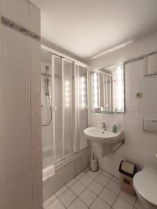 a white bathroom with a sink and a shower at Auersberg Haus in Eibenstock