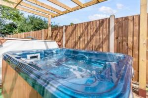 a hot tub in a backyard with a wooden fence at Amazing bungalow with hot tub in Lessingham