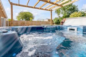 a hot tub in a backyard with a swimming pool at Amazing bungalow with hot tub in Lessingham