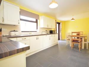 a kitchen with white cabinets and a table in it at 5 bed in Brynteg 75907 in Llanwenog