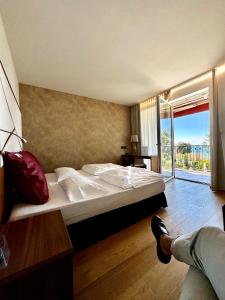 a bedroom with a large bed with a large window at Hotel Campagnola in Bardolino