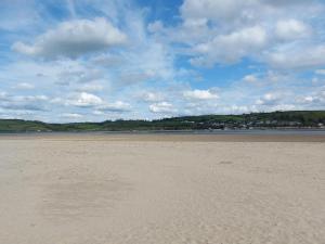 a sandy beach with a cloudy sky and water at 1 bed in Llansteffan 74267 in Ferryside