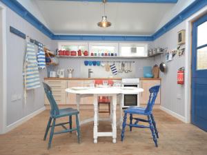 cocina con mesa blanca y 2 sillas azules en 1 bed in Llansteffan 74267, en Ferryside