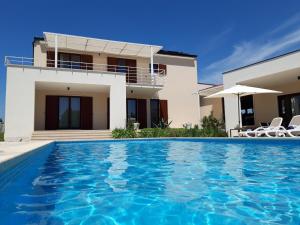 a villa with a swimming pool in front of a house at Villa Dora in Central Istria kids friendly with private pool and playground for 10 persons in Svetvinčenat +34 photos