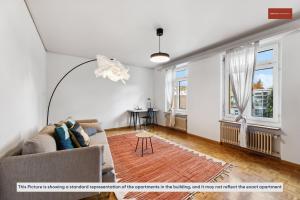 ein Wohnzimmer mit einer Couch und zwei Fenstern in der Unterkunft Spacious Apartment in Zurich in Zürich