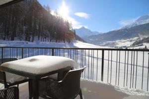 a table and chair covered in snow on a balcony at A CASA Granat in Sölden