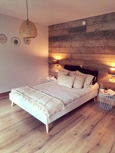 - une chambre avec un grand lit et un mur en bois dans l'établissement B&B De Geythoek, à Sijsele