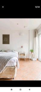 a white bedroom with a bed and a table at Appart cosy avec terrasse in Mons-en-Baroeul