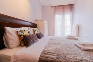 een slaapkamer met een groot bed met kussens en een raam bij Lavender 2bdrm Apartment, Vesta Philoxenia in Thessaloniki