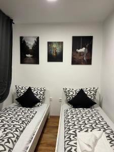 twee bedden in een kamer met schilderijen aan de muur bij City Flats Dortmund in Dortmund