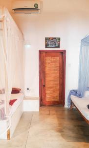Zimmer mit 2 Betten und einer Holztür in der Unterkunft Weligama Bay Eco Villa in Weligama