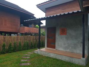 une maison avec une porte en bois et un panneau sur celle-ci dans l'établissement Kedthawa Homestay เฮือนภูผา, à Ban Cho Lae