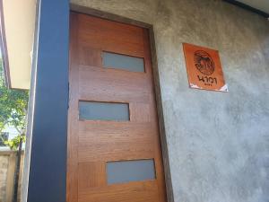 une porte en bois d'une maison munie d'un panneau. dans l'établissement Kedthawa Homestay เฮือนภูผา, à Ban Cho Lae