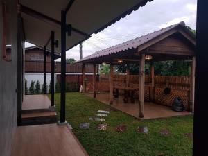 a wooden pavilion with a picnic table in a yard at Kedthawa Homestay เฮือนภูผา in Ban Cho Lae