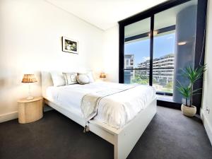 a bedroom with a white bed and a large window at French Country Style in Olympic Park in Sydney
