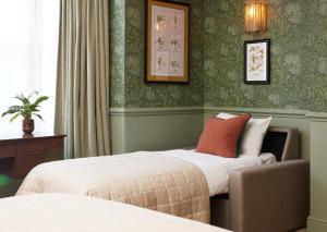 um quarto de hotel com duas camas e uma cadeira em Dog and Partridge by Greene King Inns em Bury Saint Edmunds