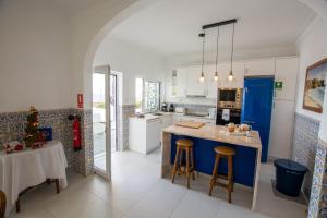 een keuken met een blauw eiland en een tafel en stoelen bij Vila Fortaleza in Aljezur