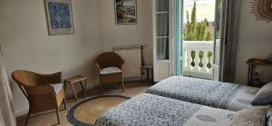 Cette chambre comprend un lit, des chaises et une fenêtre. dans l'établissement Villa Marguerite, à Hyères