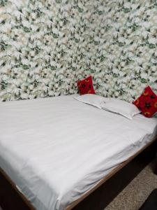 Una cama blanca con dos almohadas rojas. en Blue Cherry Guest House en Calcuta
