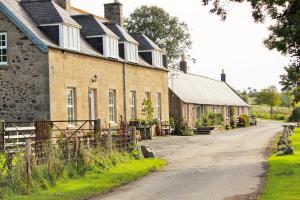 a row of old brick buildings on a dirt road at Press Mains Farm Cottages in Eyemouth