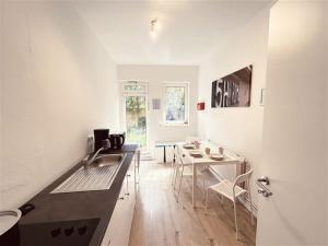 Nice Apartment in Halstenbek في Halstenbek: مطبخ مع حوض وطاولة مع كراسي