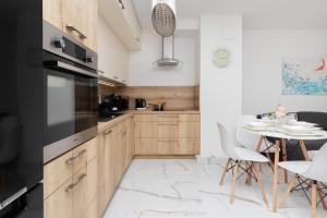 a kitchen with wooden cabinets and a table with chairs at Batorego 7 Apartament with Terrace & Parking Downtown Gdynia by Renters in Gdynia