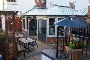 an outdoor patio with tables and an umbrella at Dog and Partridge by Greene King Inns in Bury Saint Edmunds