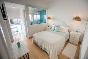 een witte slaapkamer met een bed en een spiegel bij Vila Fortaleza in Aljezur
