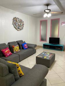 a living room with two couches and a tv at grounfloor flat furnished swimming pool in Flic-en-Flac