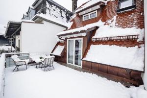 a house covered in snow with a table and chairs at Luxury Penthouse on the Lake in Überlingen